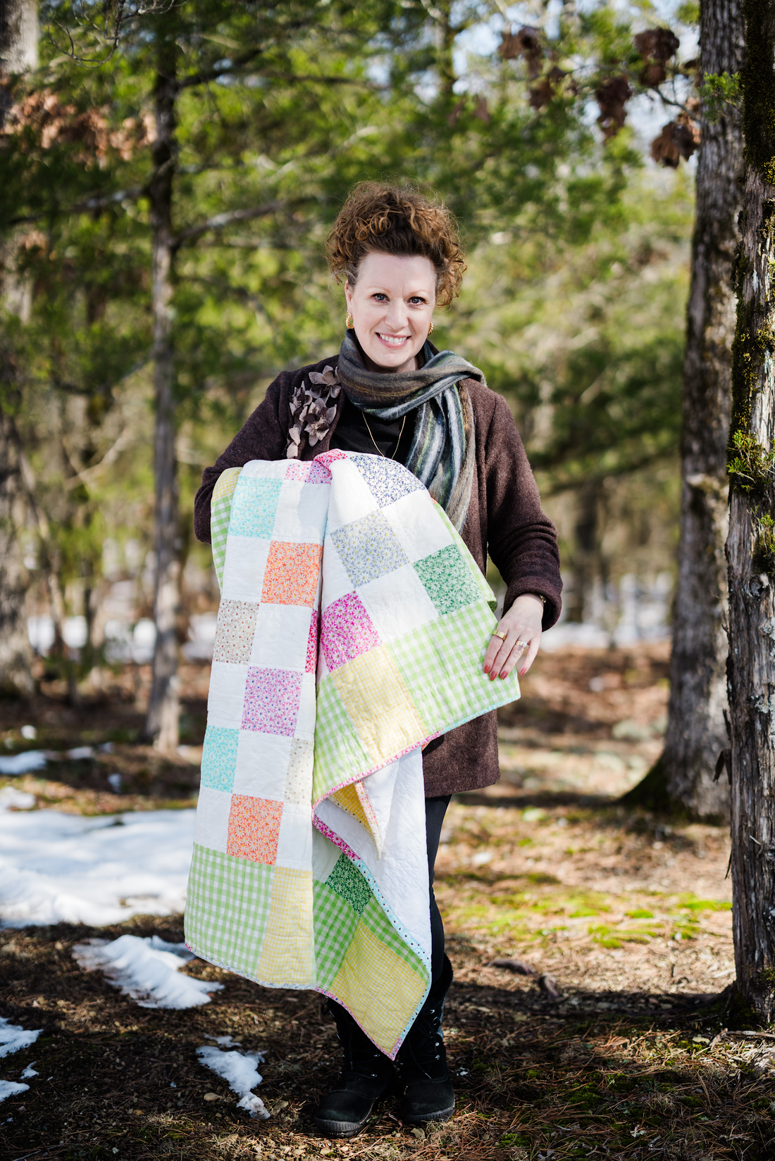 Belle Brunner holding her first patchwork quilt outdoors.