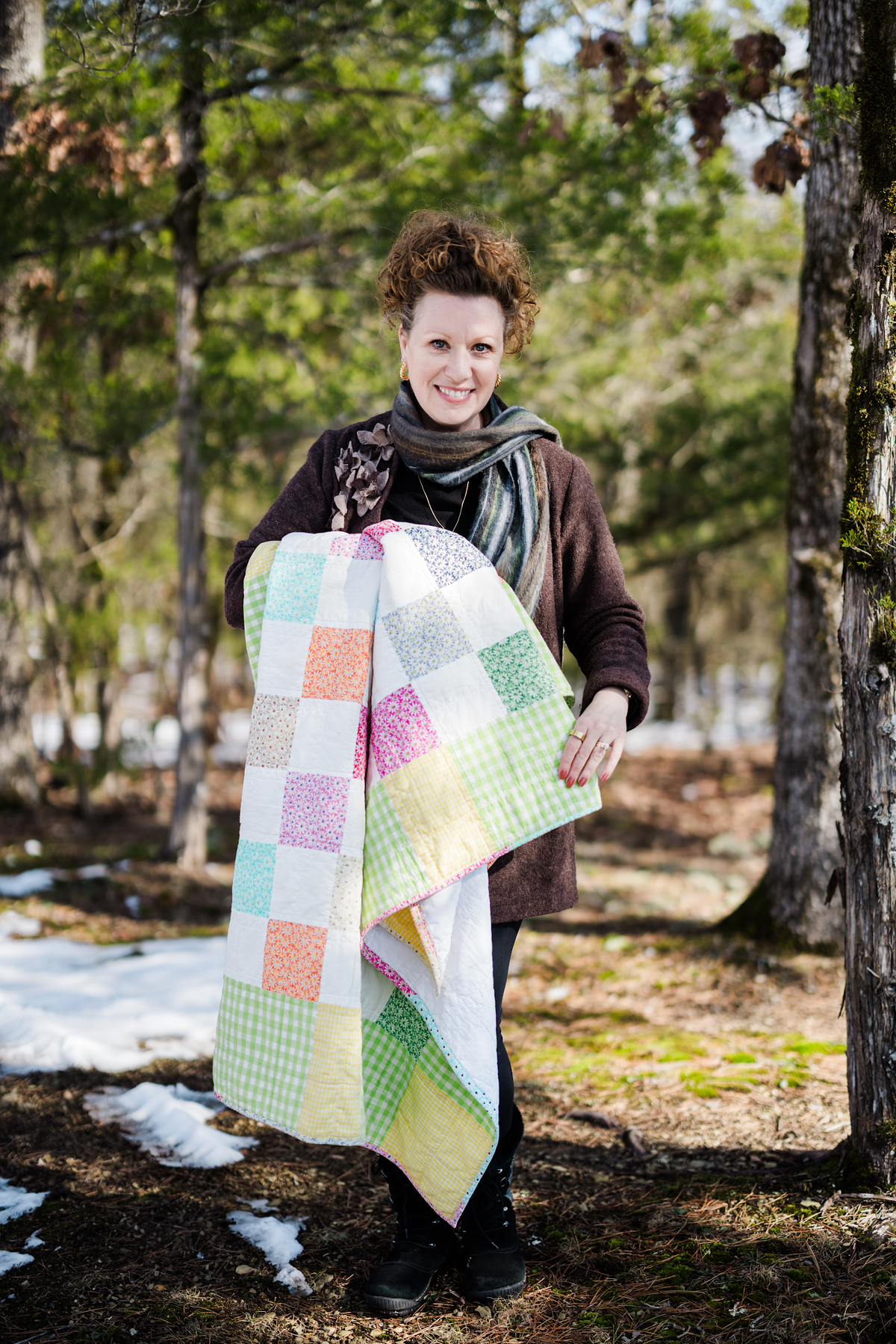 Belle Brunner holding her first patchwork quilt outdoors.