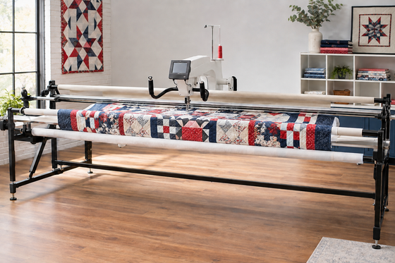Frame-mounted longarm quilting machine stitching a red, white, and navy quilt