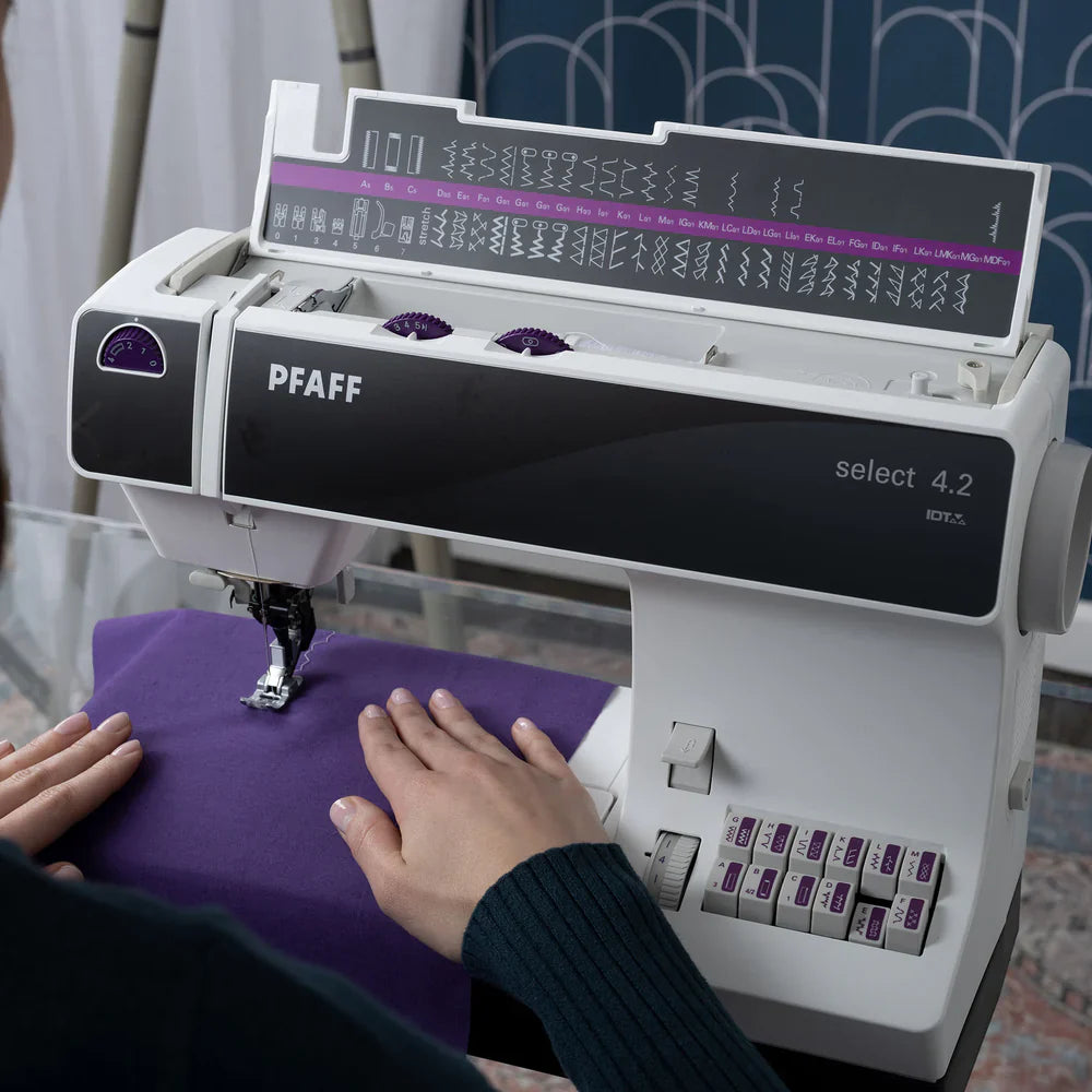 PFAFF sewing machine with a person using it on a purple fabric.