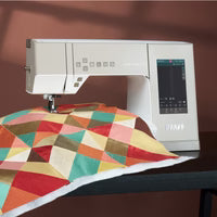 Sewing machine with a colorful geometric quilt on a brown background