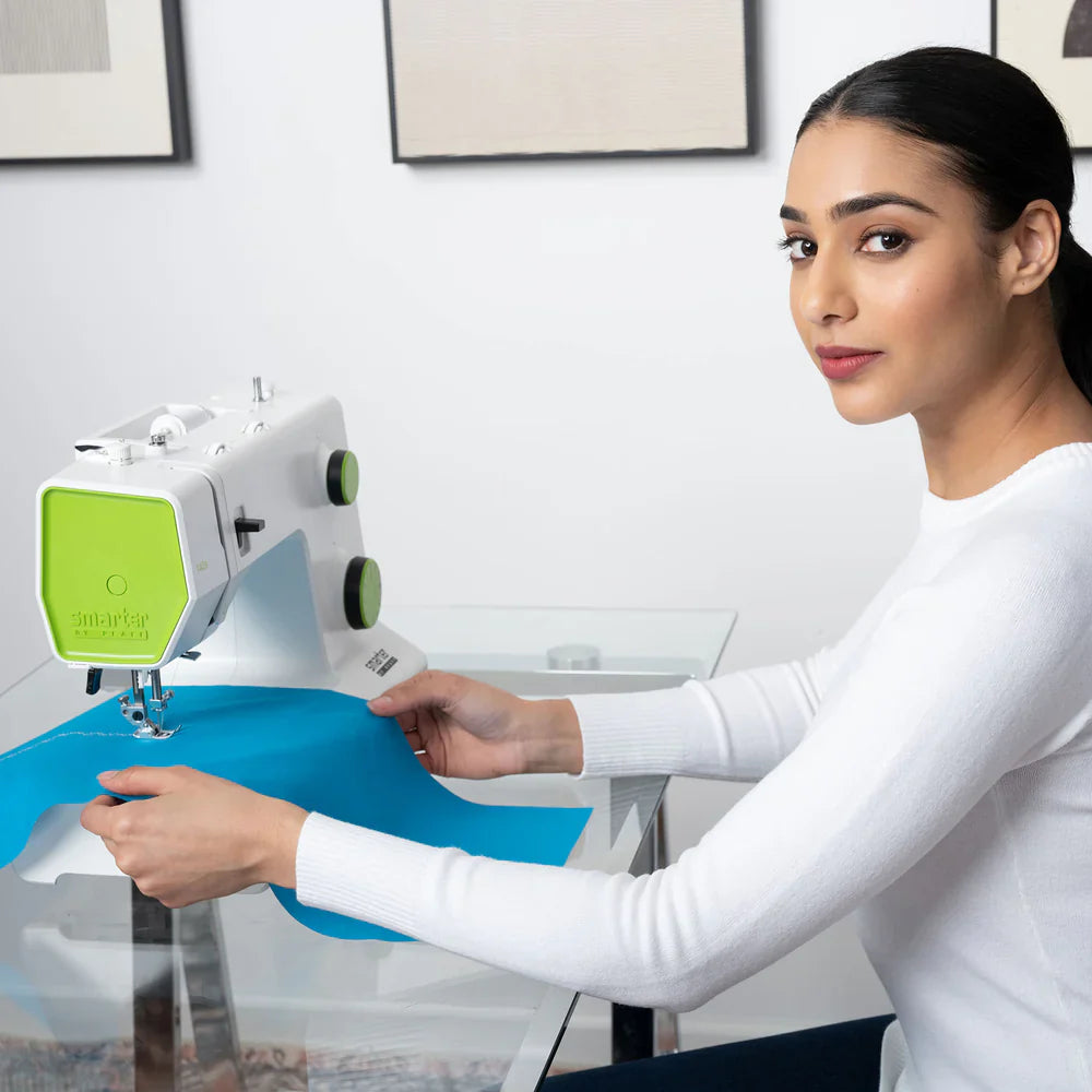 Woman using a sewing machine with a white background