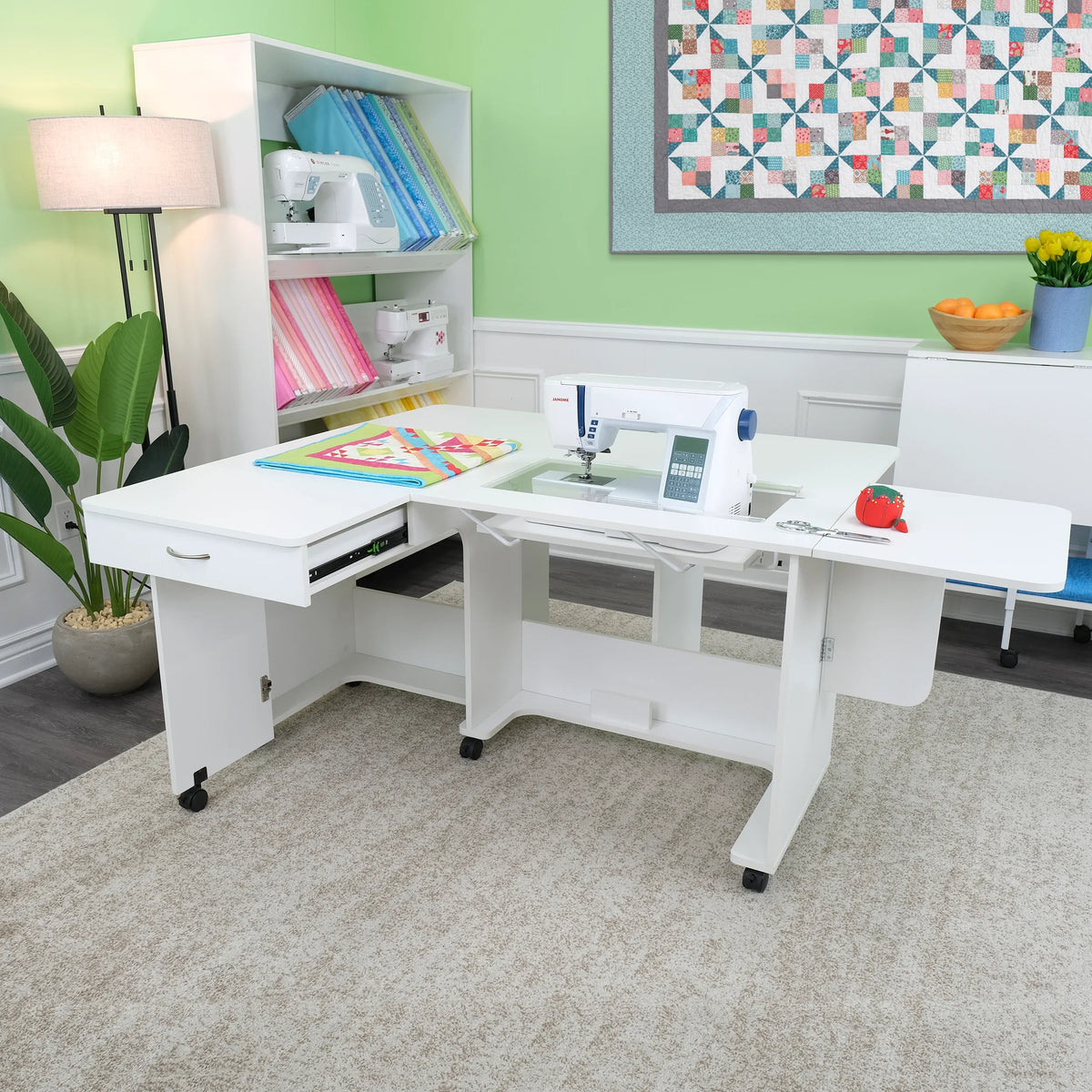 Arrow Christa Sewing Cabinet in White shown with extended quilt leaves and storage drawer open in a creative workspace.