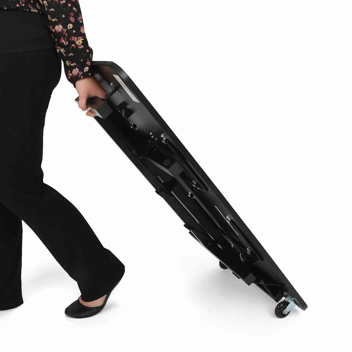Person rolling and carrying the folded Arrow Heavyweight Sewing Table 611F with built-in caster wheels