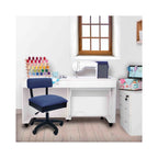 Arrow Duchess Blue Sewing Chair in sewing room setup – ergonomic blue swivel chair placed beside white sewing cabinet and machine.