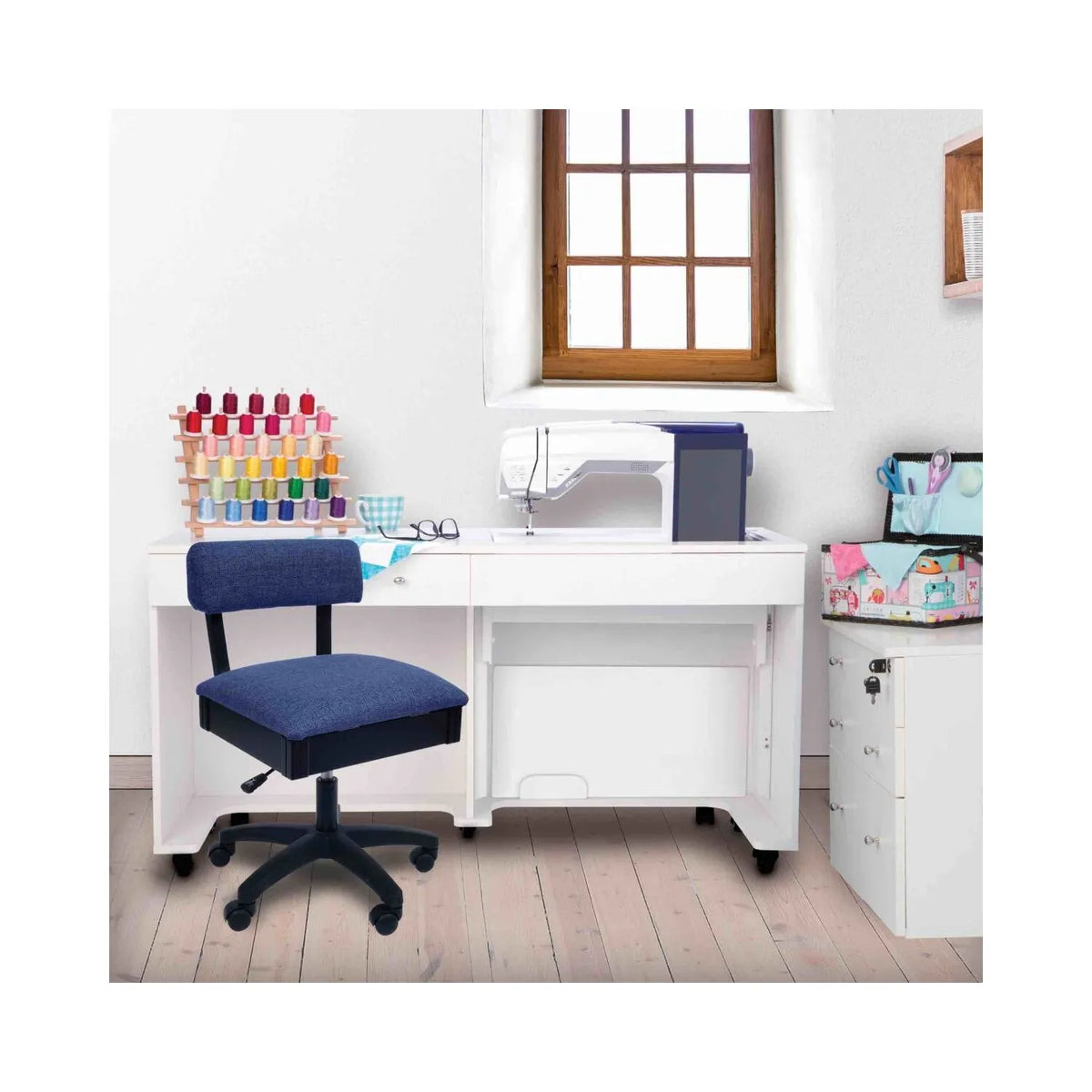 Arrow Duchess Blue Sewing Chair in sewing room setup – ergonomic blue swivel chair placed beside white sewing cabinet and machine.