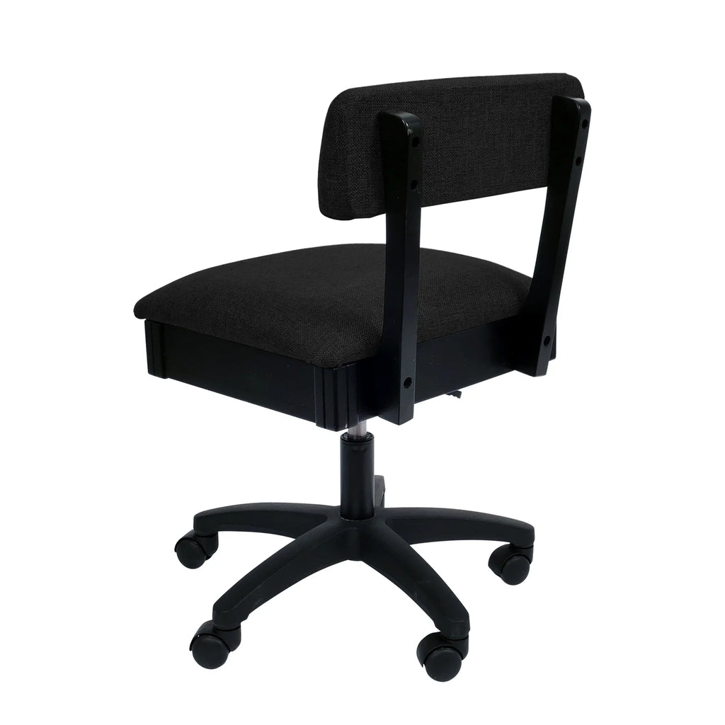 Arrow Baroness Black Hydraulic Sewing Chair – rear angle view showing black woven fabric upholstery, supportive backrest, and smooth-rolling caster wheels.