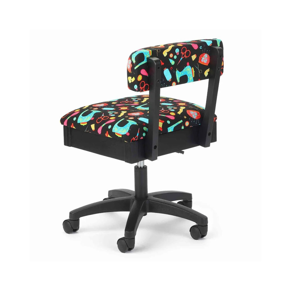 Arrow Black Notions Hydraulic Sewing Chair – rear angle view showing vibrant sewing notions pattern fabric, sturdy support frame, and smooth-rolling casters.