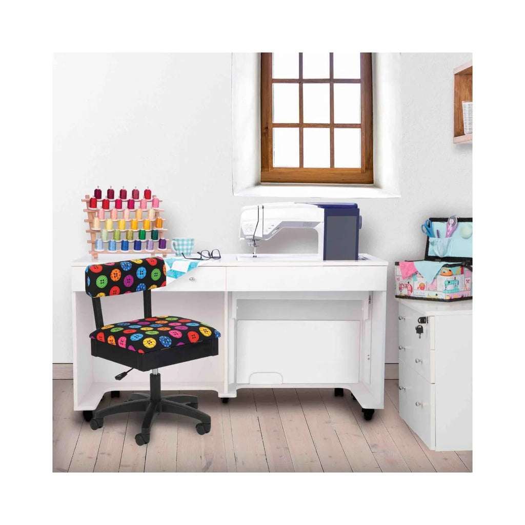 Bright Buttons Hydraulic Sewing Chair in sewing room setting – colorful button-print swivel chair placed beside white sewing cabinet and machine.