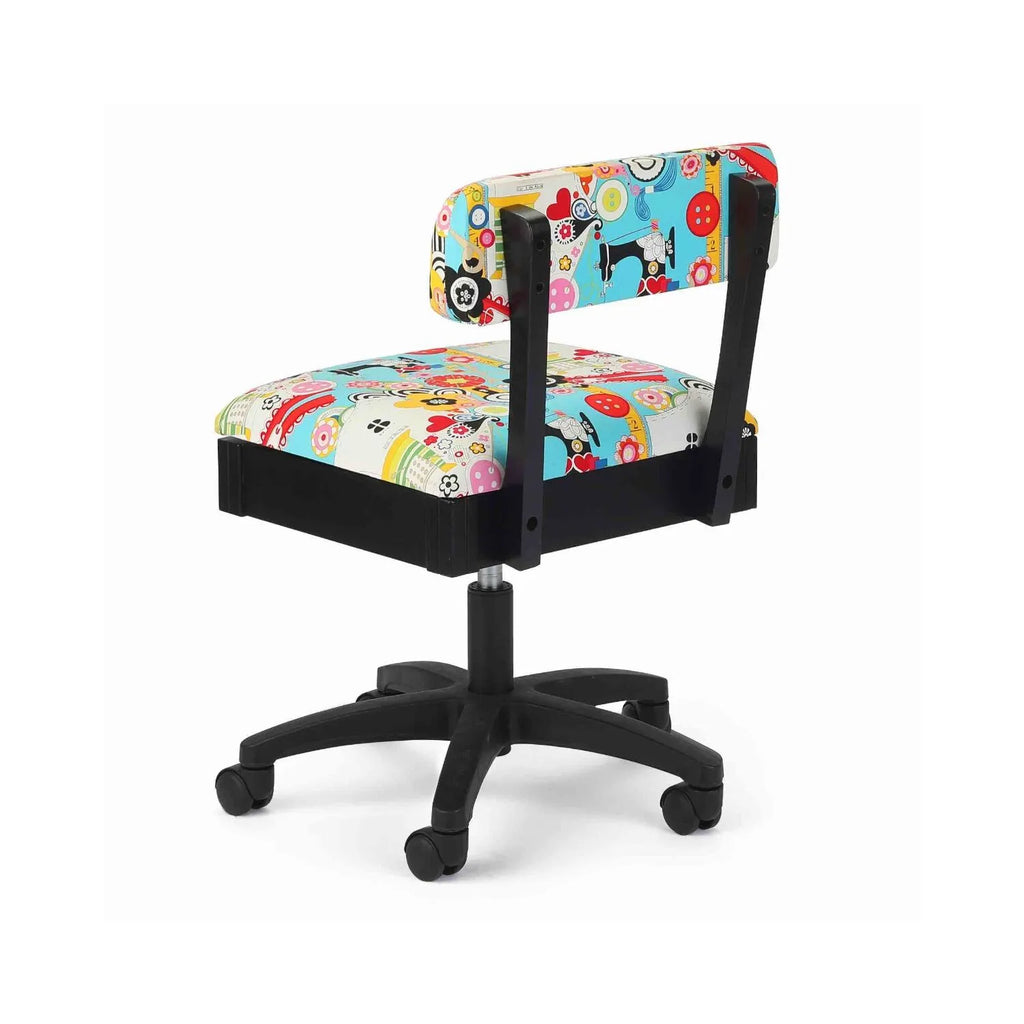 Arrow Sew Wow Hydraulic Sewing Chair – rear angle view showing bright multi-color sewing pattern fabric, sturdy support frame, and smooth-rolling casters.