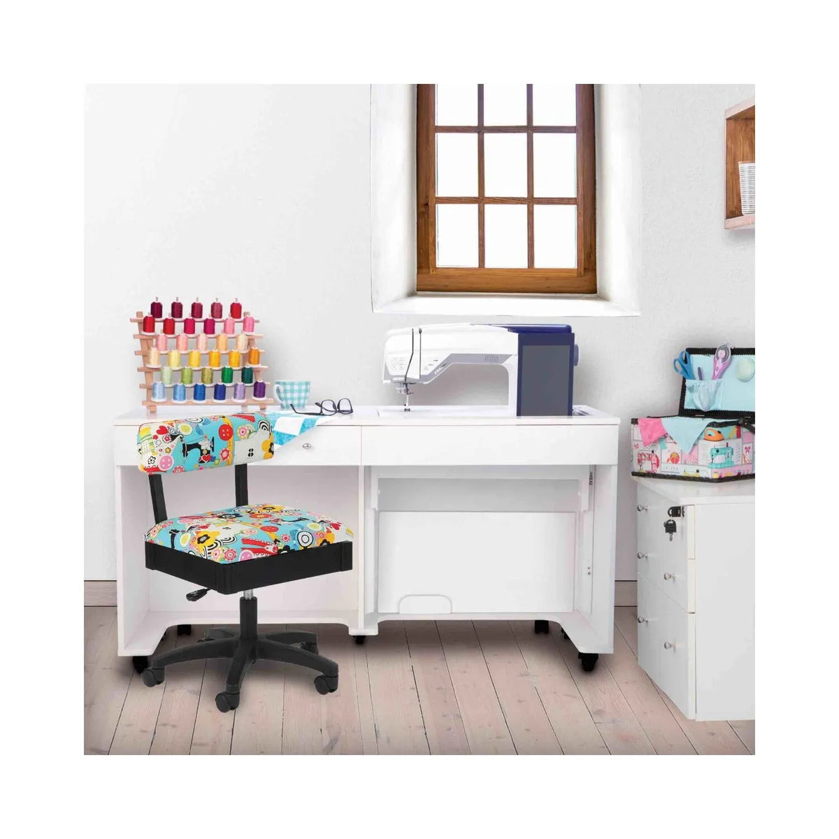 Arrow Sew Wow Hydraulic Sewing Chair in sewing room setup – colorful sewing-pattern chair paired with white sewing cabinet, machine, and crafting tools.