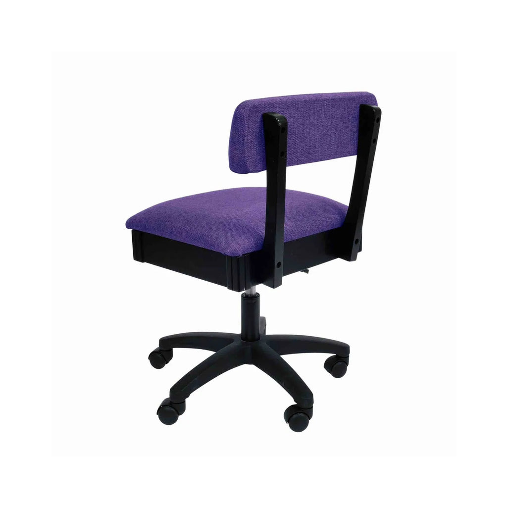Arrow Royal Purple Hydraulic Sewing Chair – rear angle view showing textured purple fabric, supportive backrest, and smooth-rolling caster wheels.