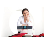 Woman sitting at a sewing machine with a white background