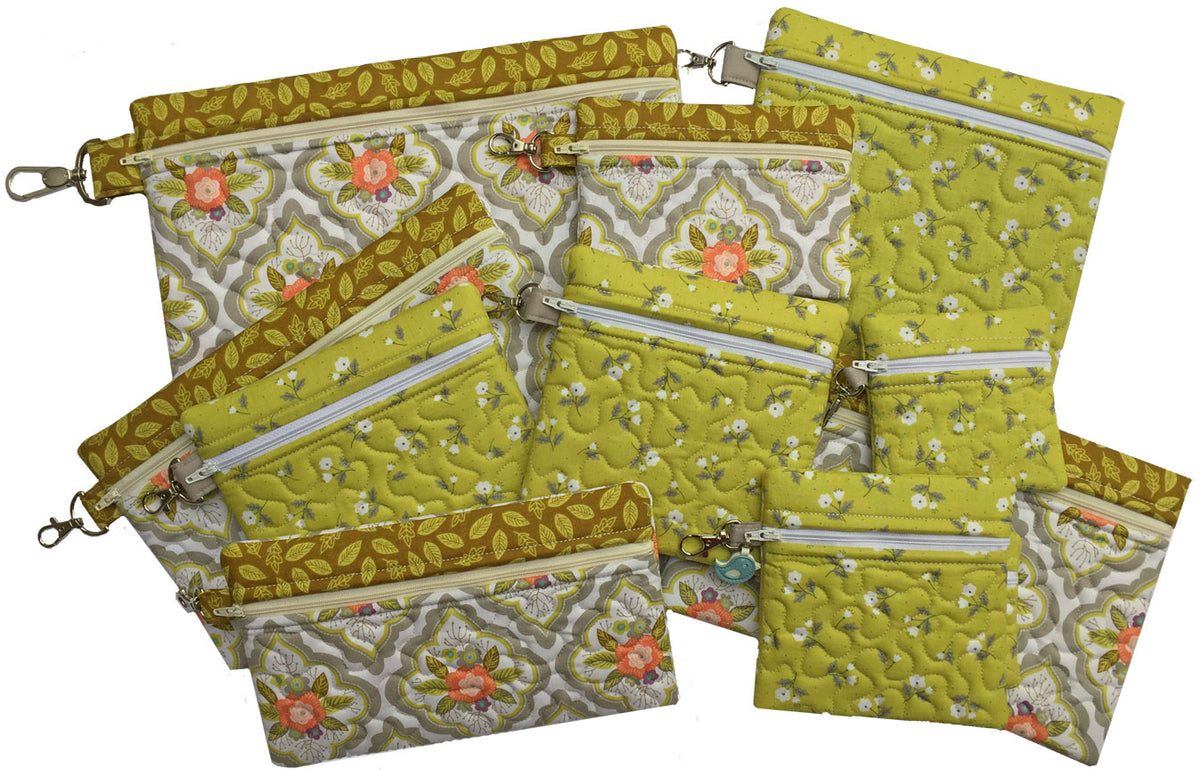 Eleven finished green and floral in-the-hoop zippered bags in square and rectangular sizes