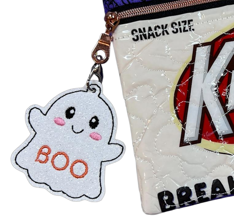 White ghost bag charm with pink cheeks and orange BOO embroidery clipped to a zippered bag