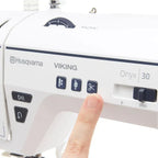 Close-up of Husqvarna Viking Onyx 30 built-in thread cutter button and function controls on the sewing machine body