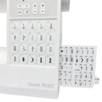Close-up of Janome Sewist 780DC slide-out stitch chart featuring decorative, utility, and buttonhole stitches.