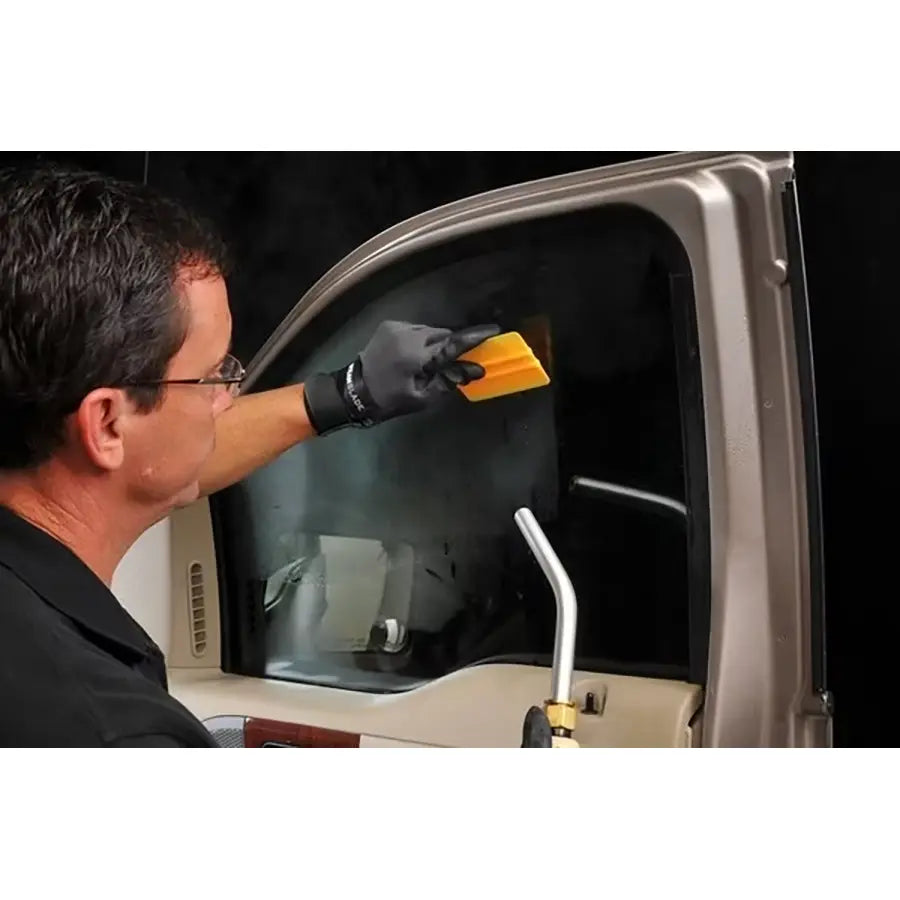 Pro installer using the SteamBlade steamer to soften adhesive on vehicle window tint