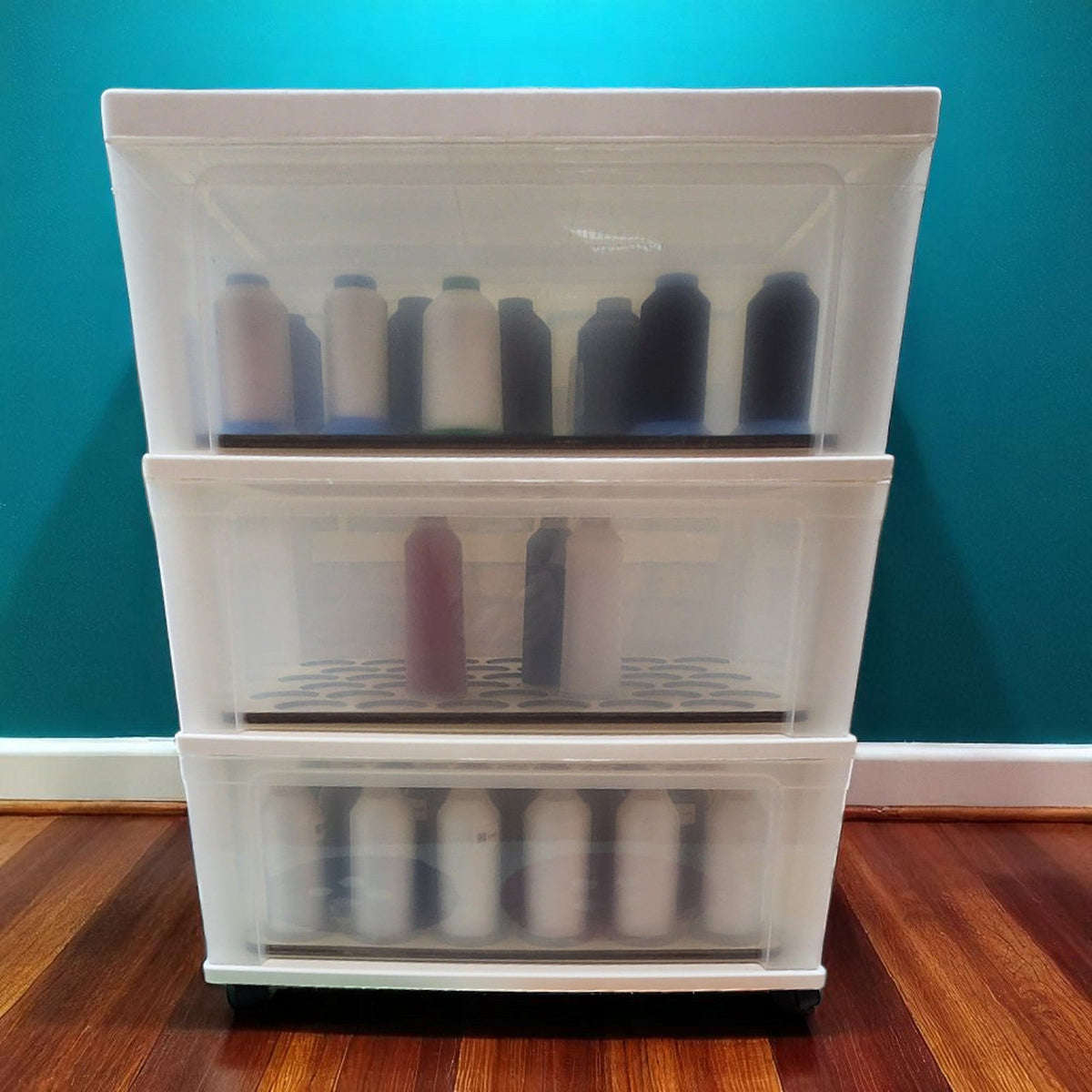 White three-drawer cart holding large spools, furniture shown for context, for King Spool Thread Storage Tray for 5,000m Spools
