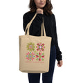 Model carrying a natural-color Floral Cheer tote with four green-and-pink quilt stars and Merry Christmas lettering.