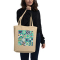 Model carrying a natural-color tote with retro geometric quilt blocks in mint green, navy and cream.