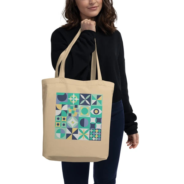 Model carrying a natural-color tote with retro geometric quilt blocks in mint green, navy and cream.