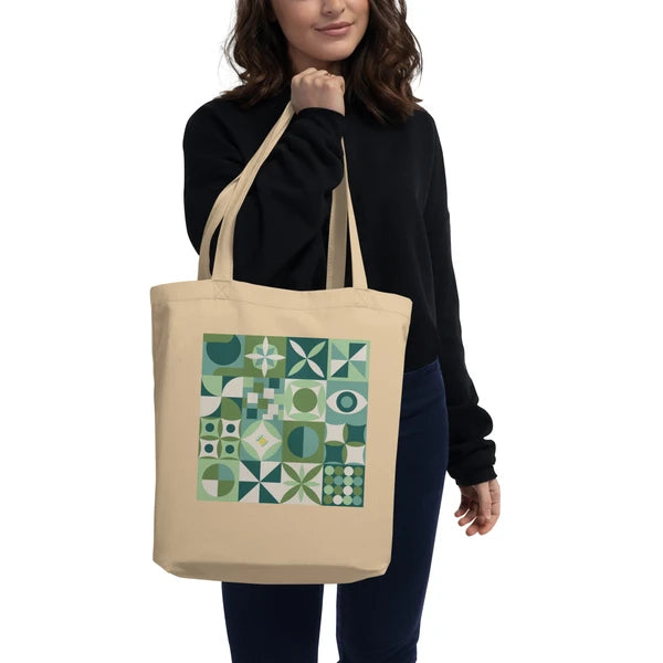 Model carrying a natural-color tote with retro geometric quilt blocks in moss green, smoky gray and cream.