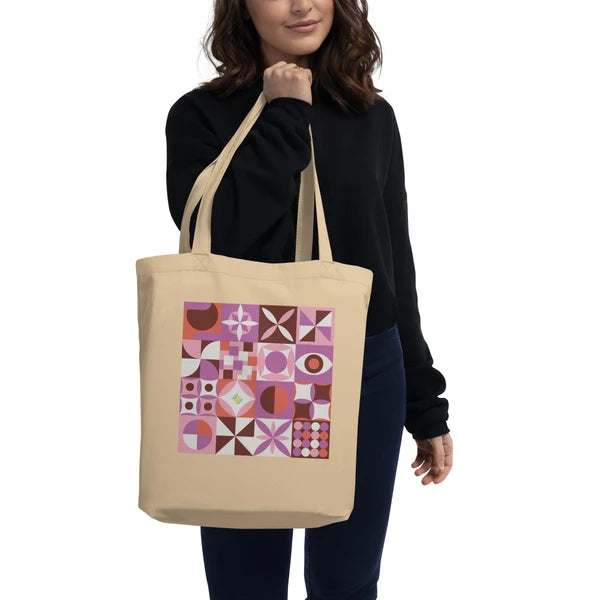 Model carrying a natural-color tote with retro geometric quilt blocks in purple, coral and cream.