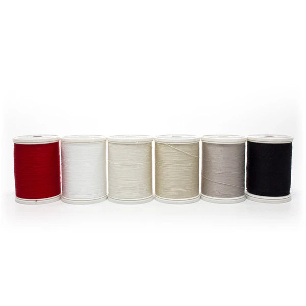 Six Sulky Essentials cotton spools lined up in red, white, off-white, beige, gray and black.