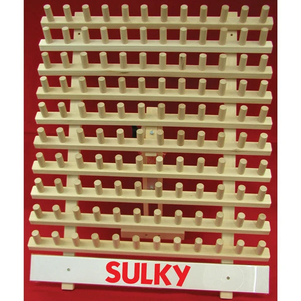 Empty wooden Sulky thread rack with rows of upright pegs and a red SULKY logo across the base.