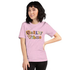 Model wearing the Heather Prism Lilac Quilty Vibes T-shirt with multicolored retro lettering across the chest.