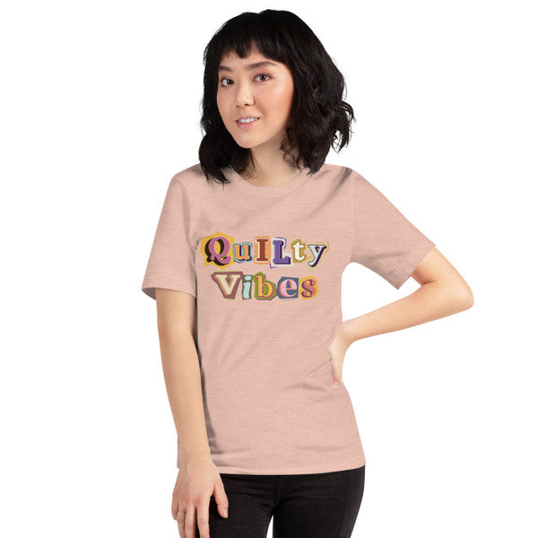 Model wearing the Heather Prism Peach Quilty Vibes T-shirt with multicolored retro lettering across the chest.