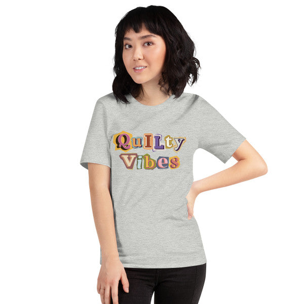 Model wearing the Athletic Heather Quilty Vibes T-shirt with multicolored retro lettering across the chest.