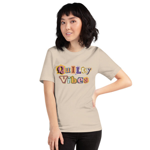 Model wearing the Soft Cream Quilty Vibes T-shirt with multicolored retro lettering across the chest.
