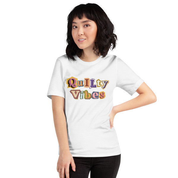 Model wearing the White Quilty Vibes T-shirt with multicolored retro lettering across the chest.