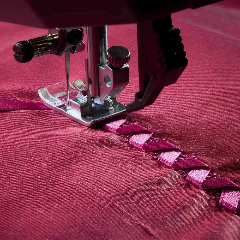 Sewing machine needle stitching a pattern on red fabric