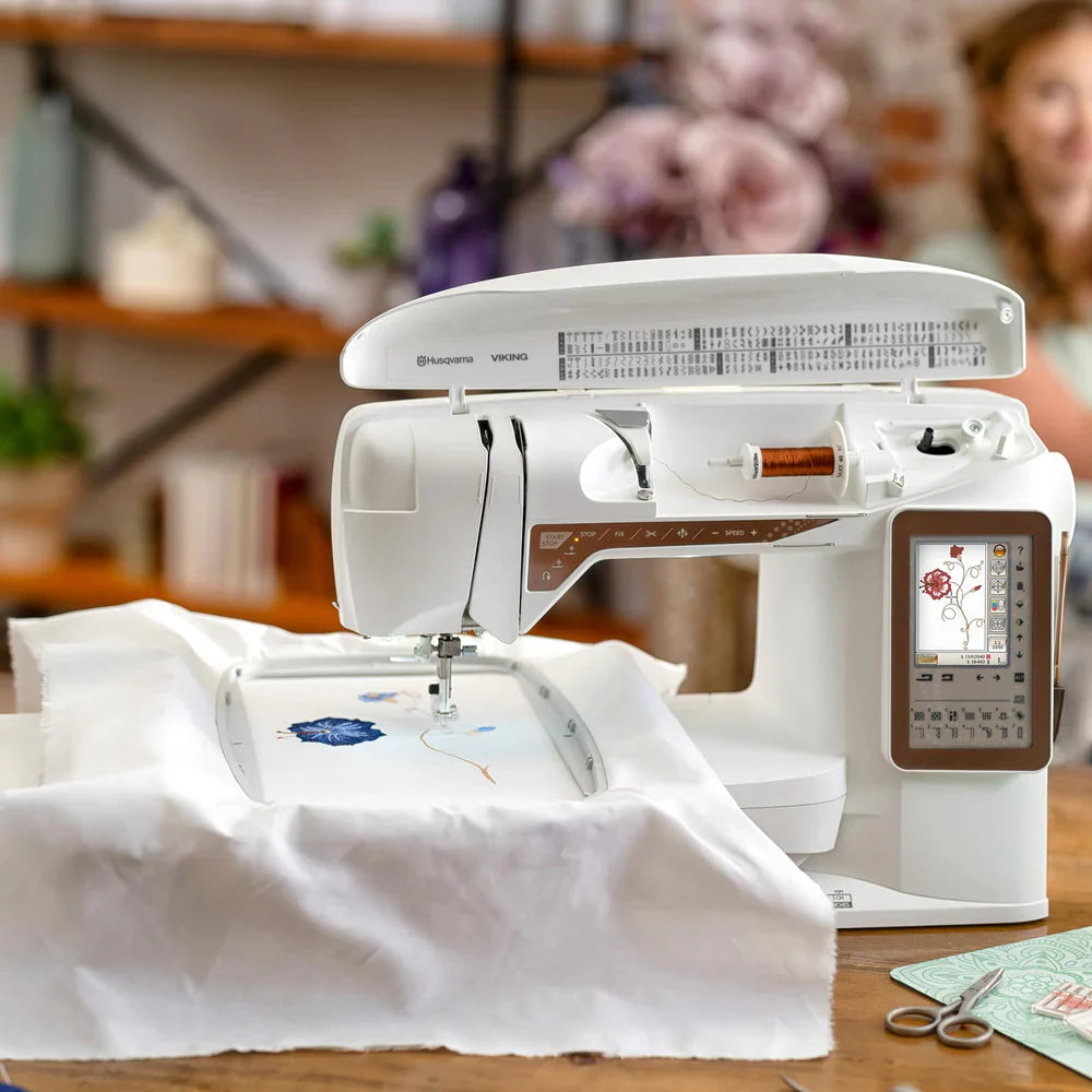 Husqvarna Viking Designer Topaz 40 embroidery machine actively stitching detailed embroidery design on fabric hoop