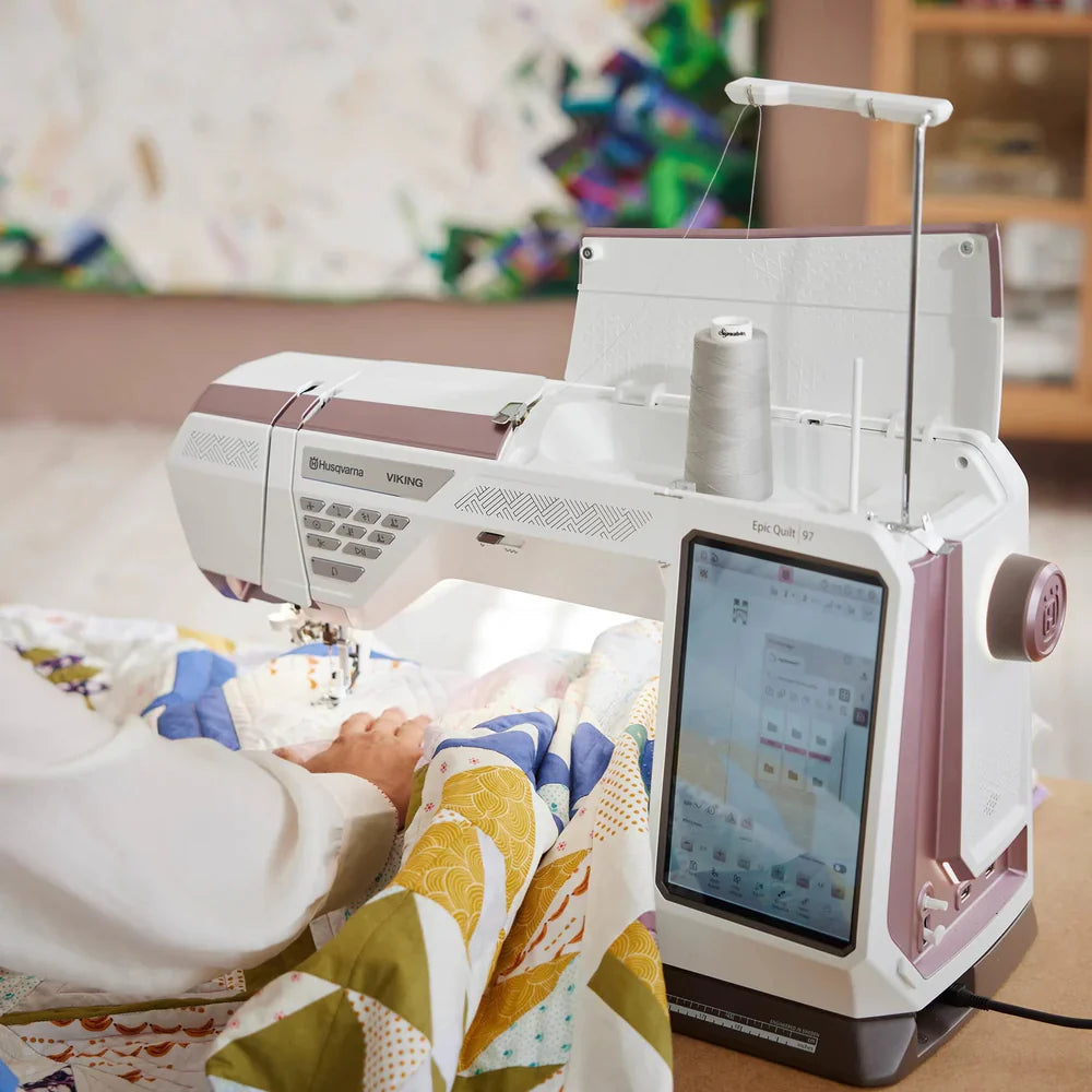 Side view of the Husqvarna Viking EPIC QUILT 97 sewing machine quilting layered fabric with intuitive touch screen controls