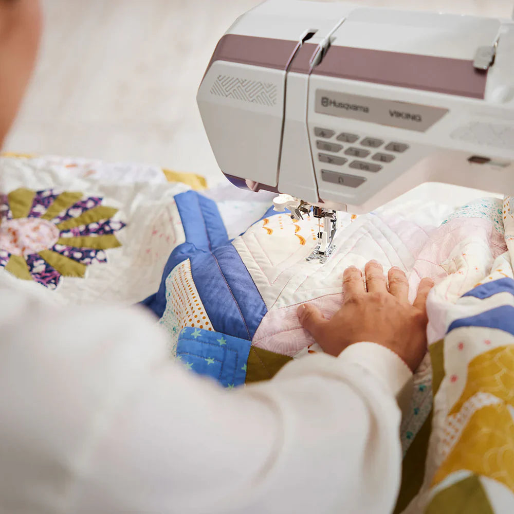 Close-up of hands guiding fabric while quilting on the Husqvarna Viking EPIC QUILT 97 sewing machine
