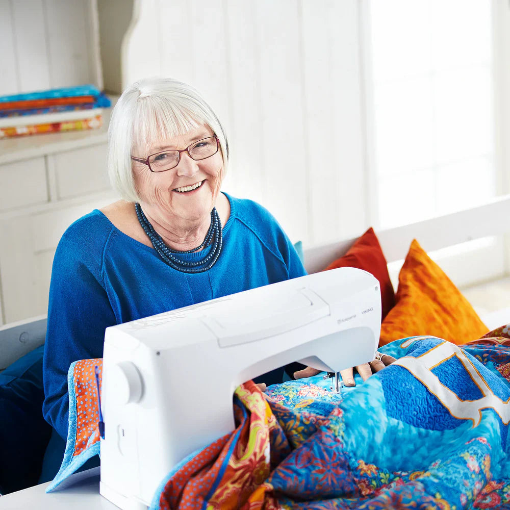 Quilter using Husqvarna Viking Sapphire 930 sewing machine on colorful quilt project with extended work surface