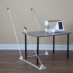 Weightless Quilter frame without a quilt, showing the floor base, angled support poles and clips around a sewing table.