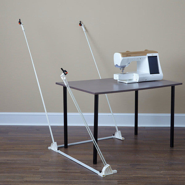 Weightless Quilter frame without a quilt, showing the floor base, angled support poles and clips around a sewing table.