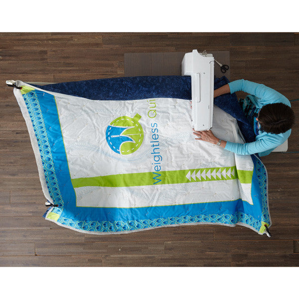 Overhead view of a quilter stitching a blue, white and lime quilt held around the machine by the Weightless Quilter frame.