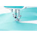 Close-up of a sewing machine needle on a light blue fabric background